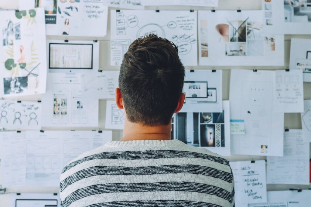 Man looking at printed data and reports on a pin board